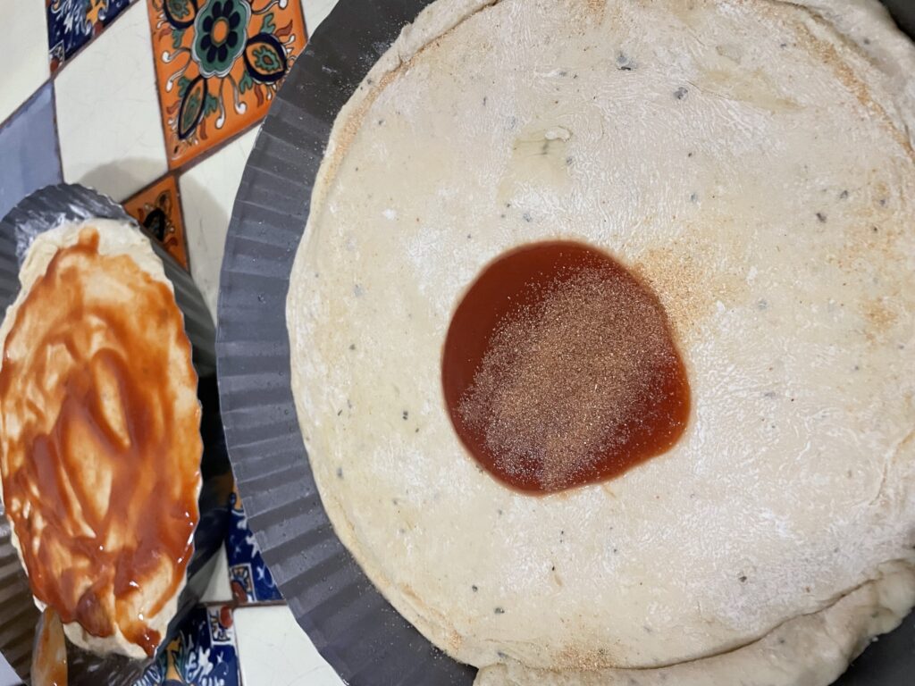 Adding pizza sauce to dough